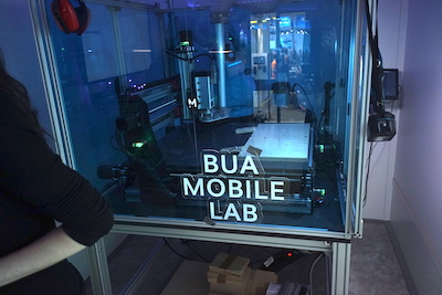 In the mobile lab interior, a CNC milling machine with a BUA mobile lab logo created with the laser cutter.
